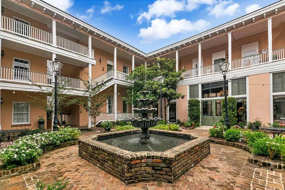 The Malaga Inn courtyard showing the twin antebellum townhouse facades with ornate wrought-iron balconies and a central fountain in Mobile, Alabama