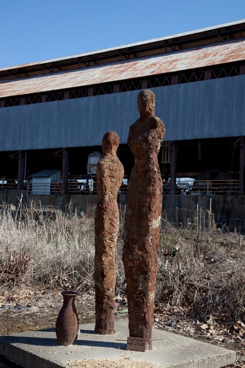 Weathered metal figure sculptures on the Sloss Furnaces grounds, standing in front of one of the furnace sheds, Birmingham, Alabama, 2010.
