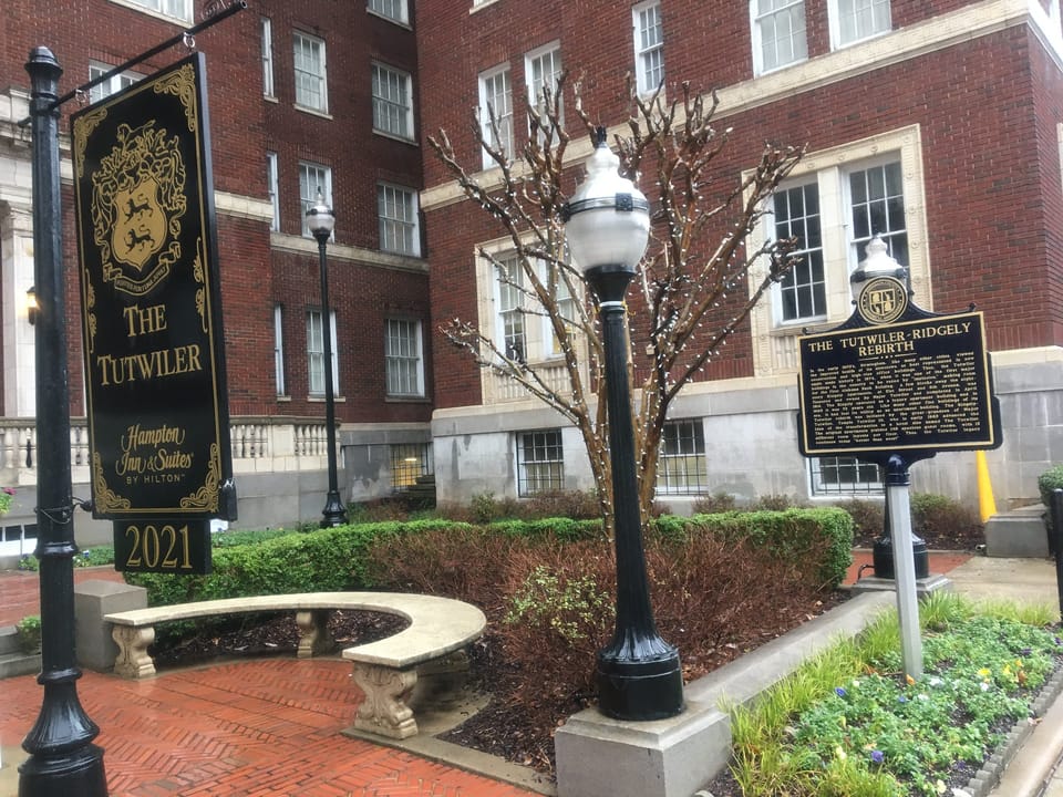 The Tutwiler's entrance garden with its lit sign reading "The Tutwiler" and a historical marker plaque, Birmingham, Alabama, February 2020.