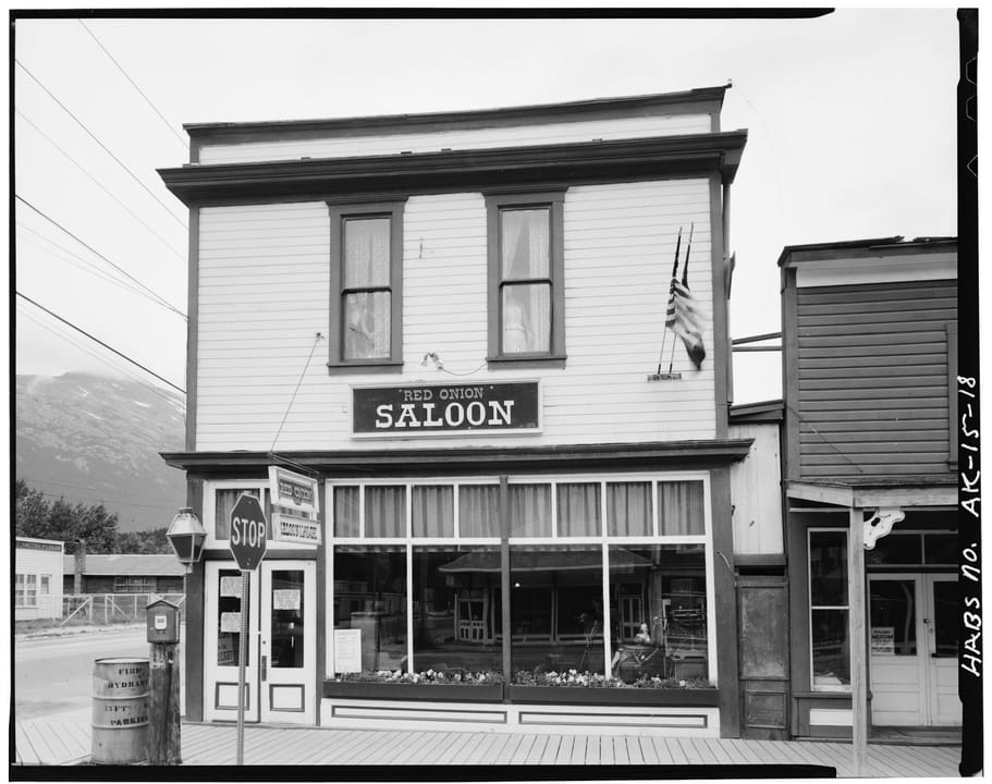 The Red Onion Saloon (built 1898) at the northwest corner of Broadway and Second Avenues, Skagway, Alaska, in a black-and-white Historic American Buildings Survey photograph with a flag flying from the roofline.