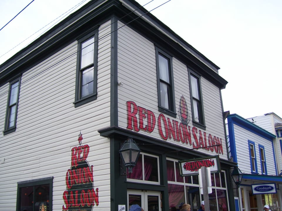 Close-up of the corner of the Red Onion Saloon in Skagway, Alaska, showing the painted sign and mural on the building's siding.
