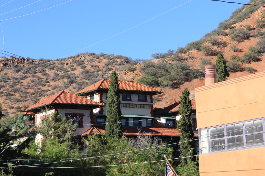 A hillside view of the Copper Queen Hotel's red-tile roofline rising above Bisbee's historic district, against the Mule Mountains.