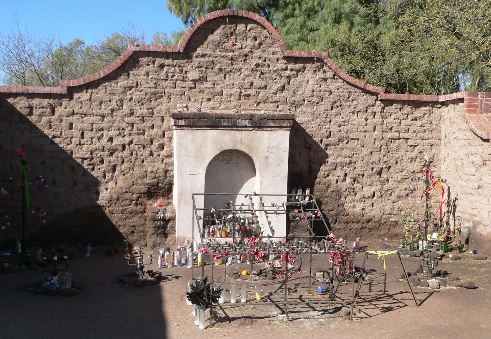 El Tiradito wishing shrine with candles and offerings against a weathered adobe wall in Tucson's Barrio Viejo