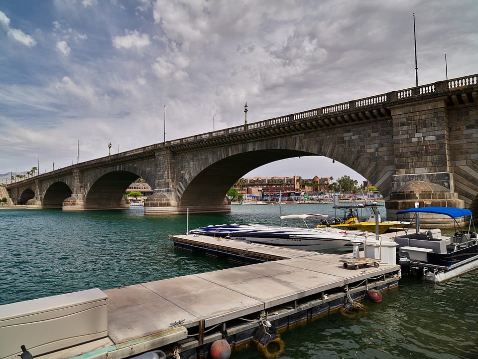 A daytime view of the bridge from the marina dock area, Lake Havasu City, Arizona, with boats moored beneath the arches.