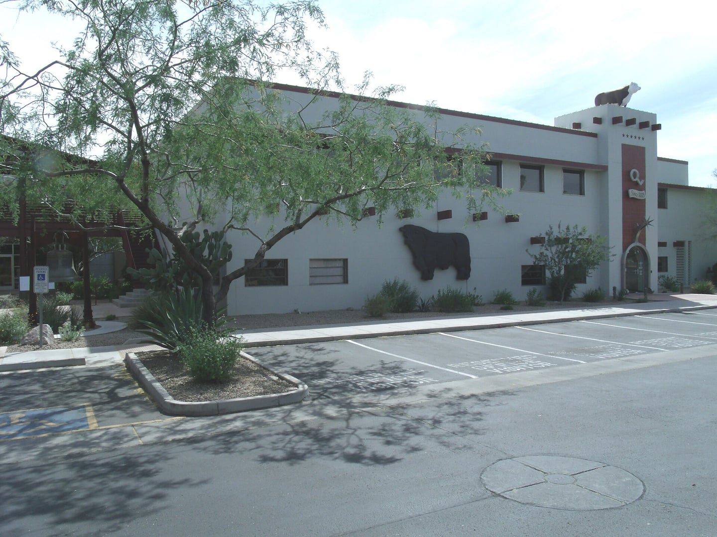Exterior of the Tovrea-era Stockyards Steakhouse building at 5009 East Washington Street in Phoenix, Arizona, showing the white stucco facade with bull sculpture and desert landscaping