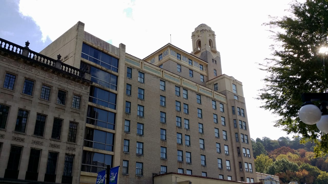 A low-angle view of the Arlington Hotel's clock tower and upper floors against the sky.