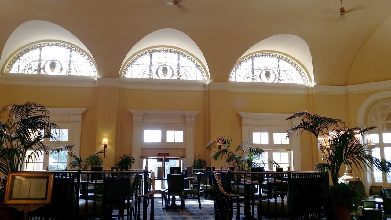 Public lobby and dining room of the Arlington Hotel in Hot Springs, Arkansas, with three arched fanlight windows and a palm-lined seating area, photographed in October 2015.