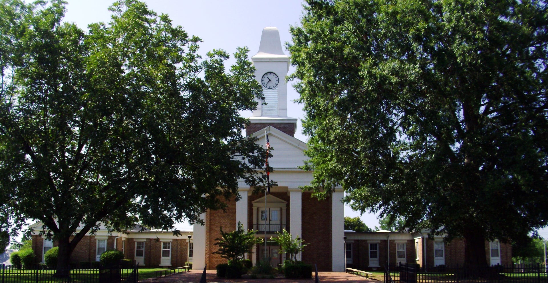 The 1964 Greek Revival Grant County Courthouse on the public square in Sheridan, Arkansas, photographed on a clear summer day.