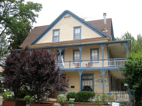 Two-story Victorian bed and breakfast with white siding and wraparound veranda in Georgetown, California