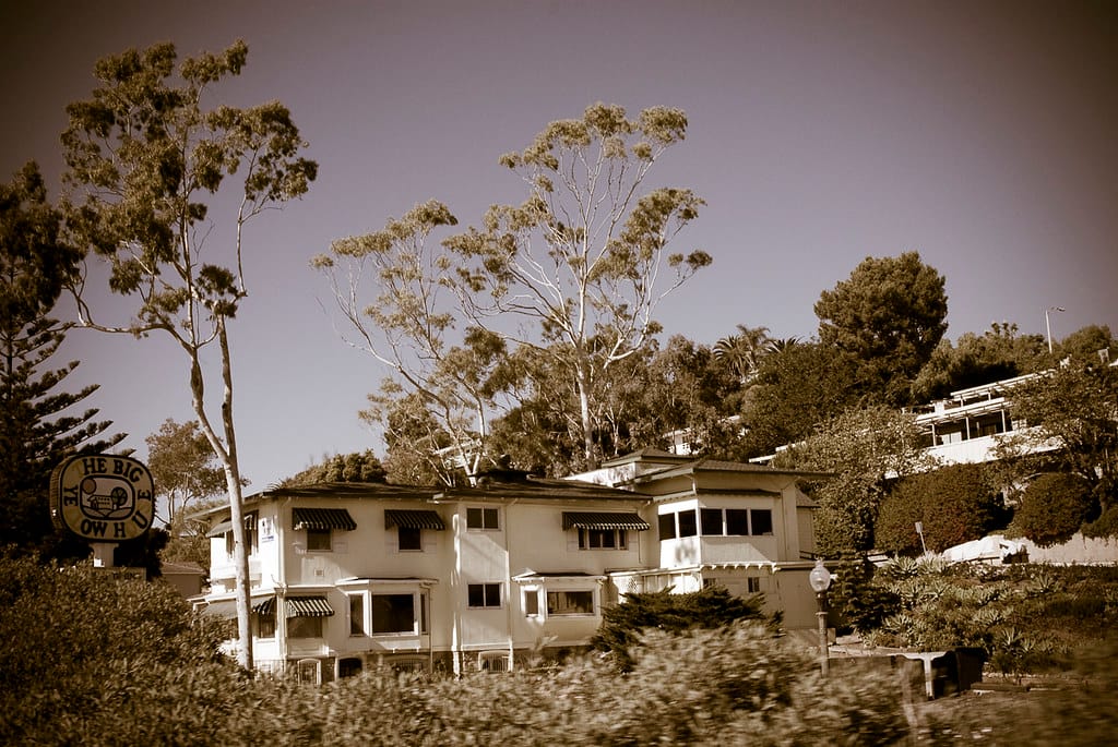 The Big Yellow House, a multi-story cream/yellow building in Summerland, California, with its round roadside sign reading 'The Big Yellow House' at the driveway entrance, 2016.