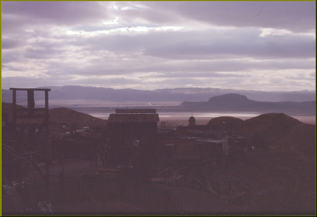 (1 in a multiple picture set)
This picture was taken on a 1980 visit to Calico, CA.  I was at the east end of Main Street, looking down upon the desert and mountains as the sun was setting.  In a little while, I turned around and saw the ghost town in a whole different perspective.  The old building
