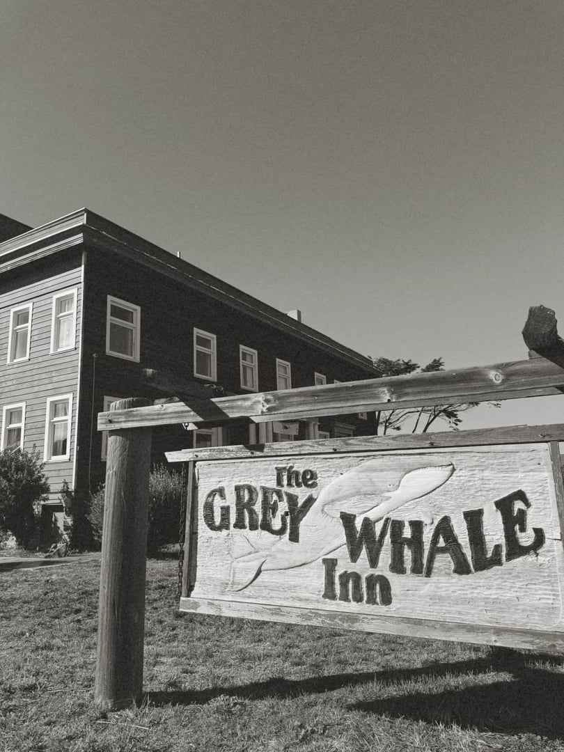 Exterior of The Grey Whale Inn in Fort Bragg CA, a historic redwood building with a hand-painted whale-themed sign.