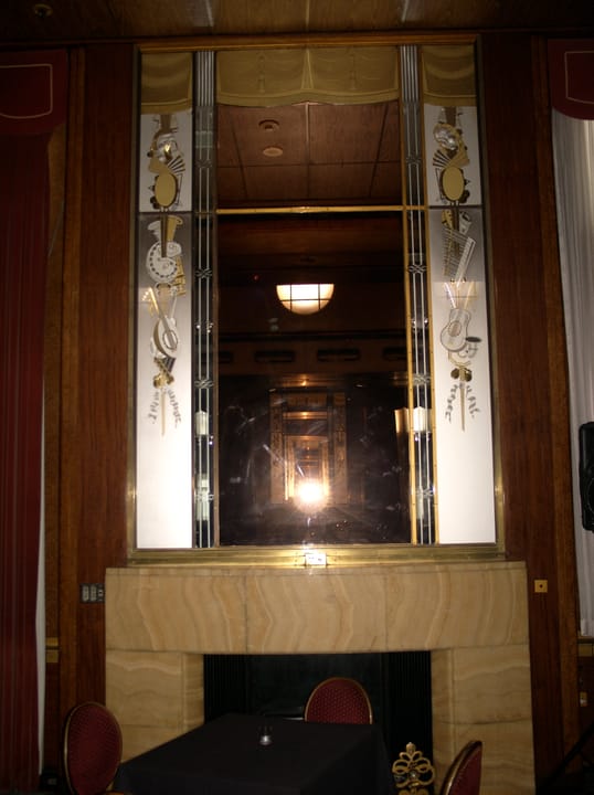 A mirrored Art Deco elevator lobby aboard the Queen Mary, with etched glass panels and brass fittings.
