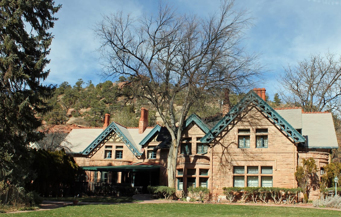A winter view of Briarhurst Manor (the William A. Bell House) in Manitou Springs, Colorado, with bare trees framing the sandstone facade.