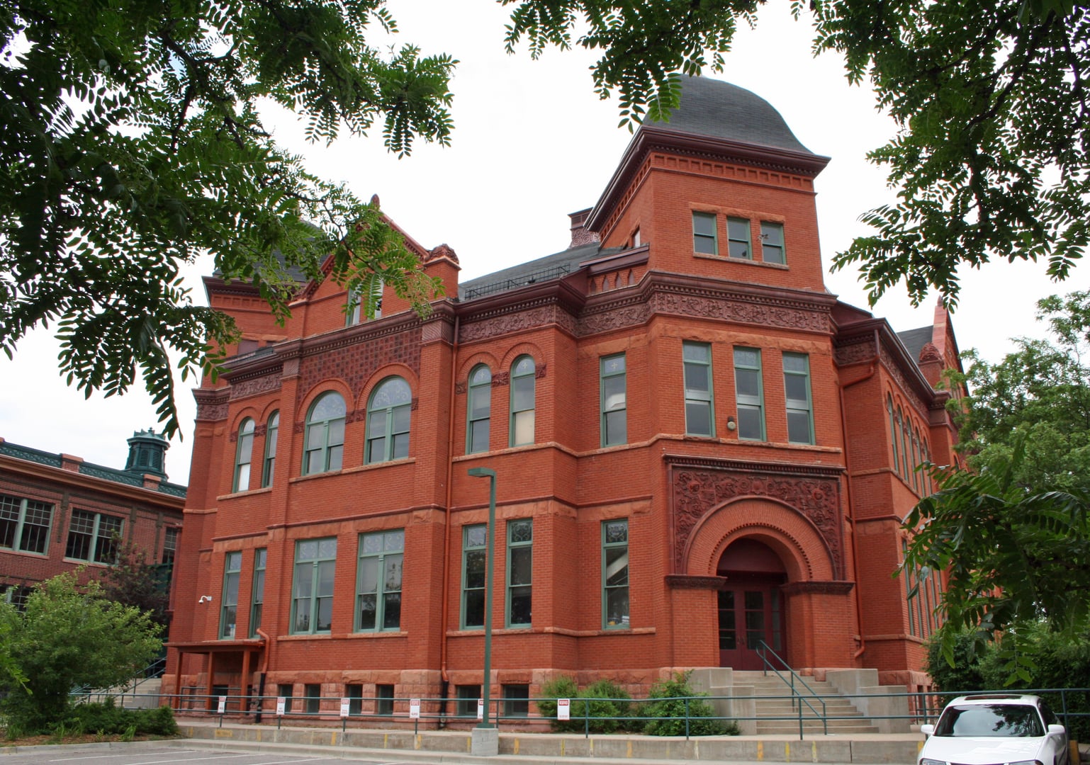 The Romanesque Revival sandstone facade of Dora Moore School, an 1890 historic landmark in Denver's Capitol Hill neighborhood.