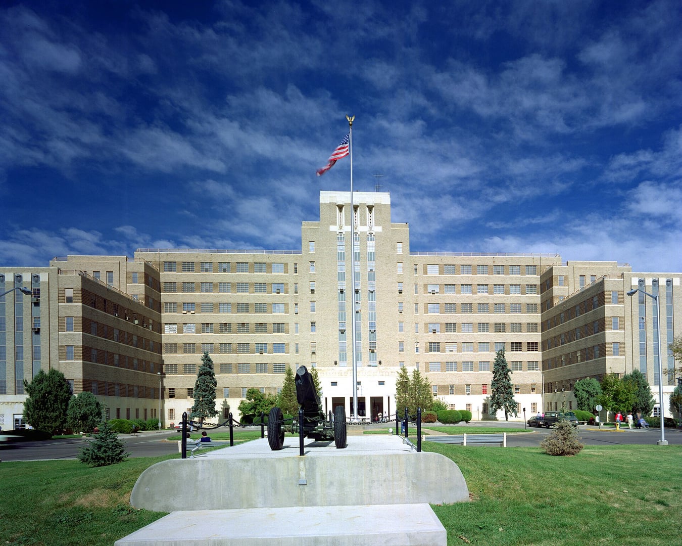 Exterior front view of Fitzsimons Army Medical Center Hospital in Aurora, Colorado, with a 75mm M116 Pack Howitzer in front, photographed in 1989