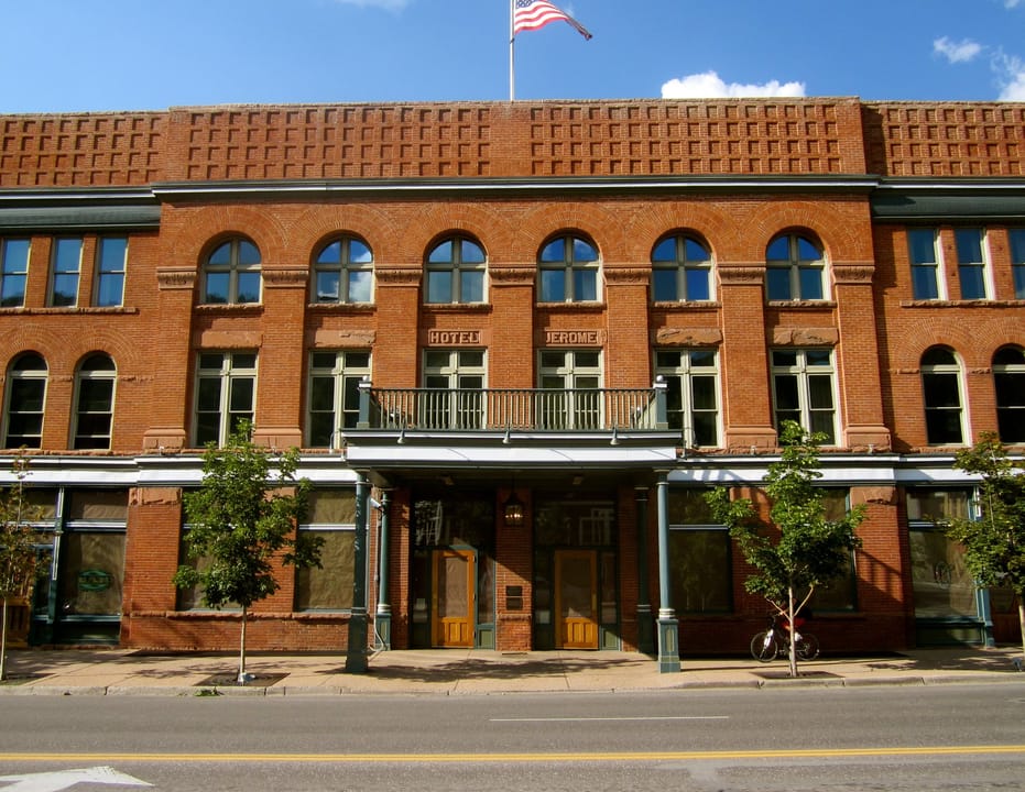 A straight-on street-level view of the Hotel Jerome's brick facade and ground-floor arcade, Aspen, Colorado.