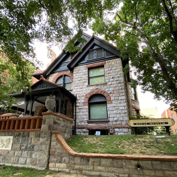 A green-season corner view of the Molly Brown House's stone and shingle facade with its museum sign, Denver, Colorado - a different angle and season than the hero's snow-covered view.