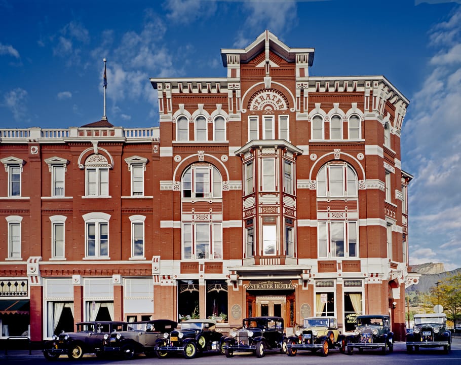 The Strater Hotel's entrance facade with a row of antique automobiles parked along the curb, Durango, Colorado.