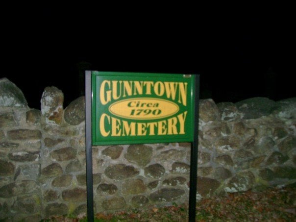Green Gunntown Cemetery sign reading 'Circa 1790' mounted before a weathered Colonial-era stone wall in Naugatuck, Connecticut