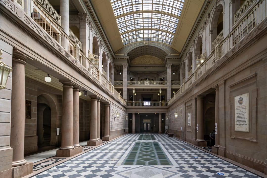 The three-story central atrium of Hartford City Hall, lit by its skylight, with a checkerboard marble floor and colonnaded galleries, 2020.