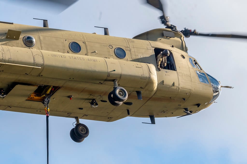 A crewmember of a CH-47 Chinook helicopter belonging to the Connecticut National Guard's 169th Aviation Regiment watches the Bambi bucket as the helicopter prepares to capture water from a local lake to dump on a brushfire burning on Lamentation Mountain in Berlin, Connecticut Oct. 23, 2024. This wa