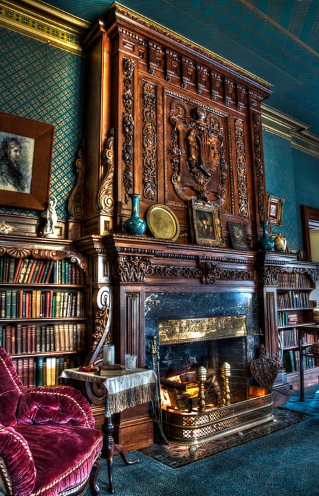 The carved library fireplace and book-lined walls inside the Mark Twain House, a room open to museum visitors on the house tour