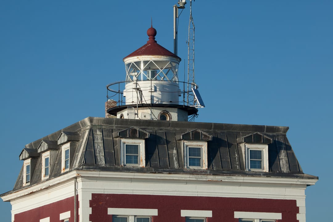 The red-roofed Second Empire dwelling and short cylindrical lantern tower of the New London Ledge Lighthouse on the Thames River in Connecticut