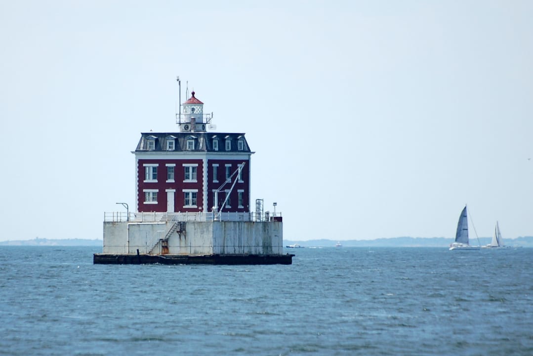 New London Ledge Lighthouse seen from the water with a sailboat passing in the background, 2007.