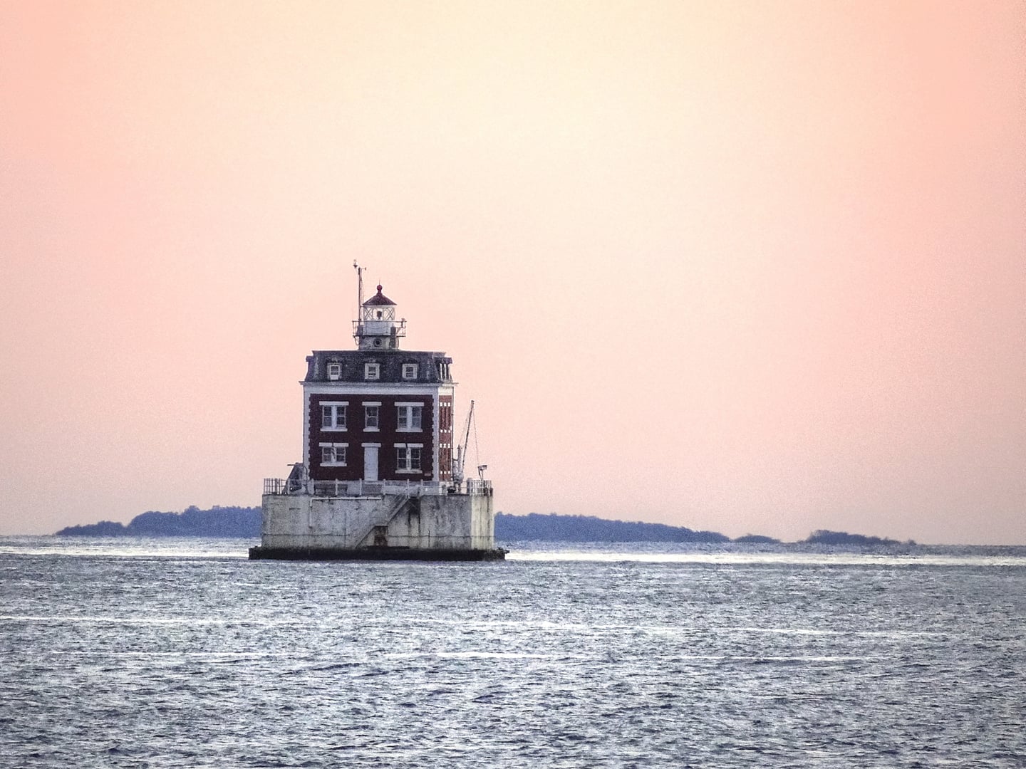 The red-roofed Second Empire dwelling and short cylindrical lantern tower of the New London Ledge Lighthouse on the Thames River in Connecticut