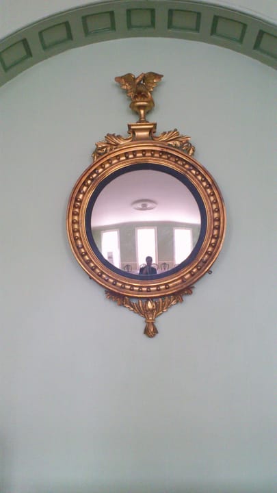 A gilt convex ("bullseye") mirror in the dining room of the Octagon, a period decorative detail of the museum interior.