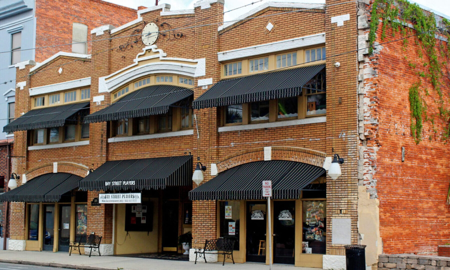 Historic 1922 brick facade of The State Theatre of Eustis with awnings and Bay Street Players signage on North Bay Street in downtown Eustis, Florida