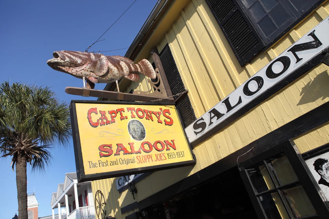 Hanging grouper sign and "CAPT. TONY'S SALOON" entrance sign on the facade of Captain Tony's Saloon, Key West