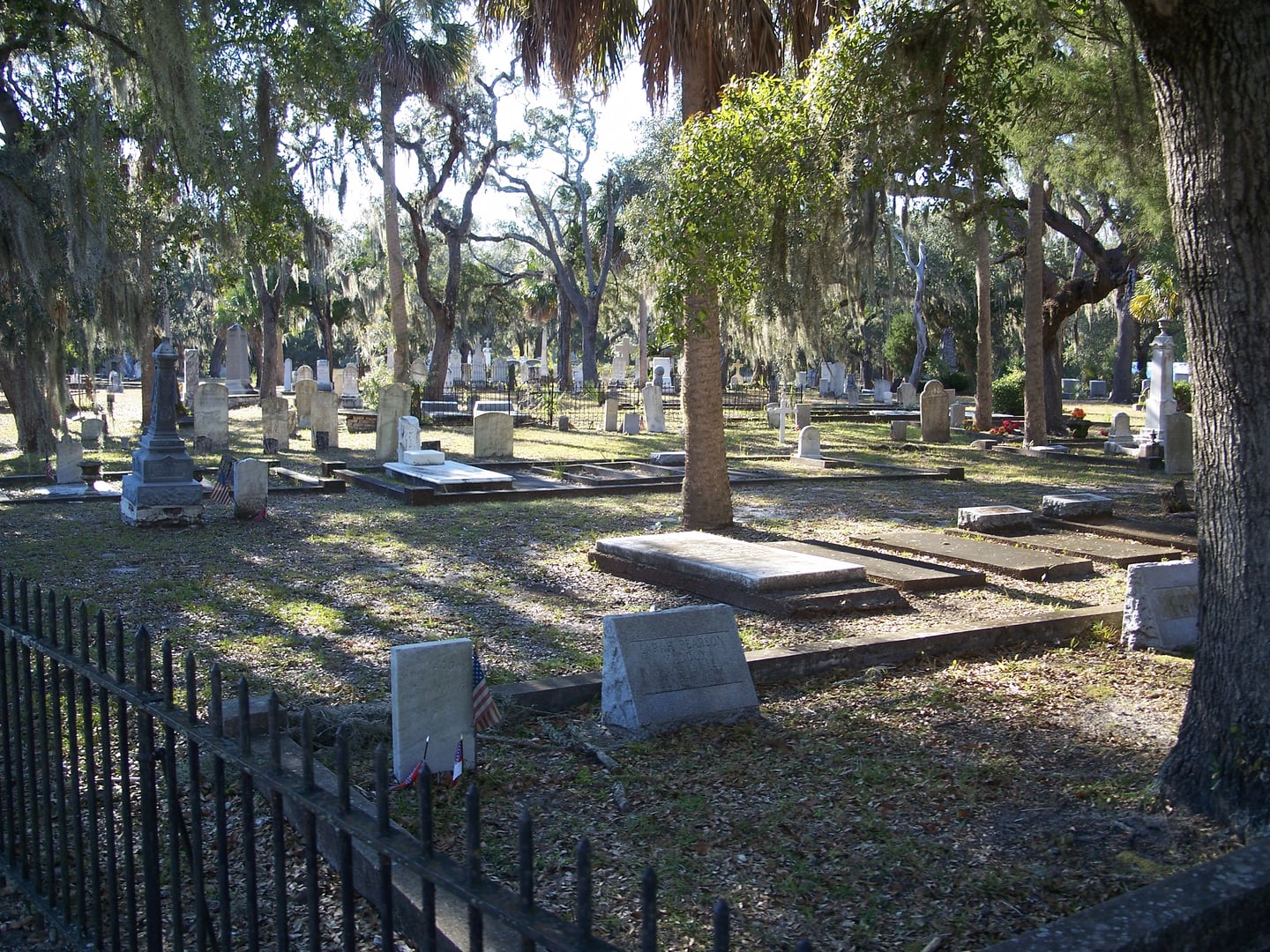 Historic tombstones ranging from 1830s vertical slabs to Victorian marble monuments at Chestnut Street Cemetery in Apalachicola, Florida