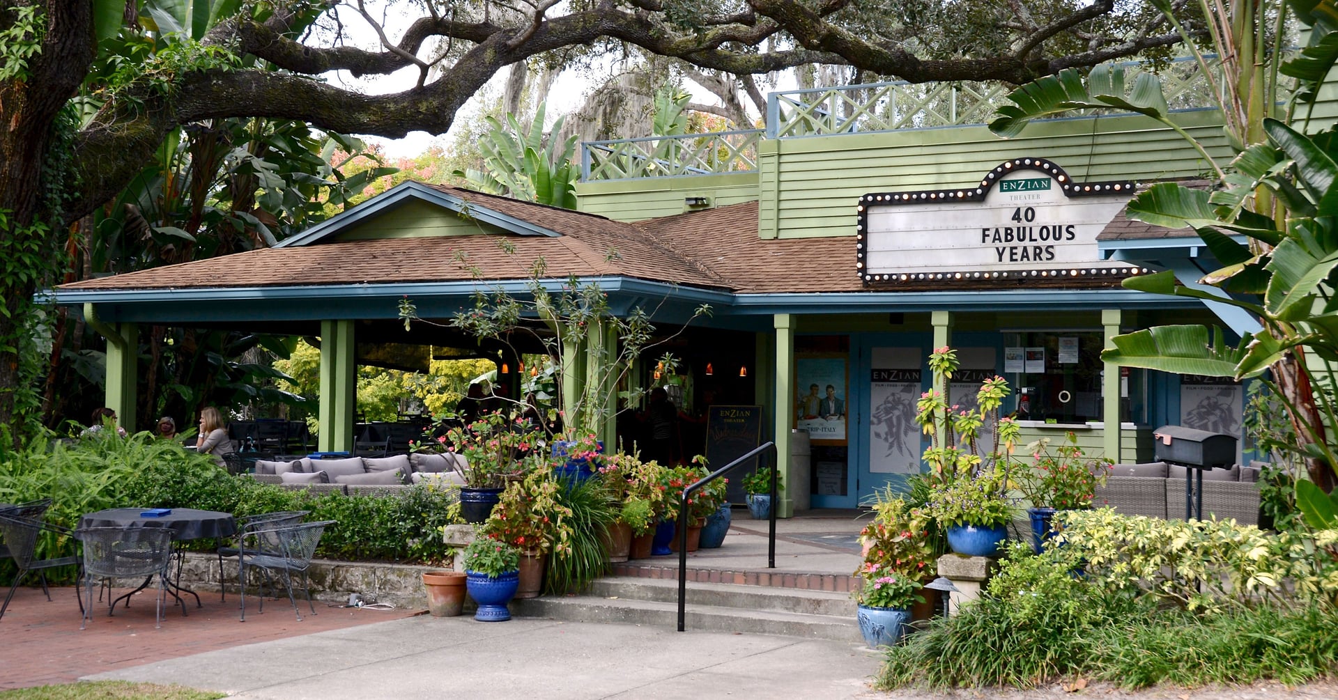 Exterior of the Enzian Theater in Maitland, Florida — a green single-screen arthouse cinema surrounded by oak trees and tropical plantings, with a marquee reading 40 Fabulous Years