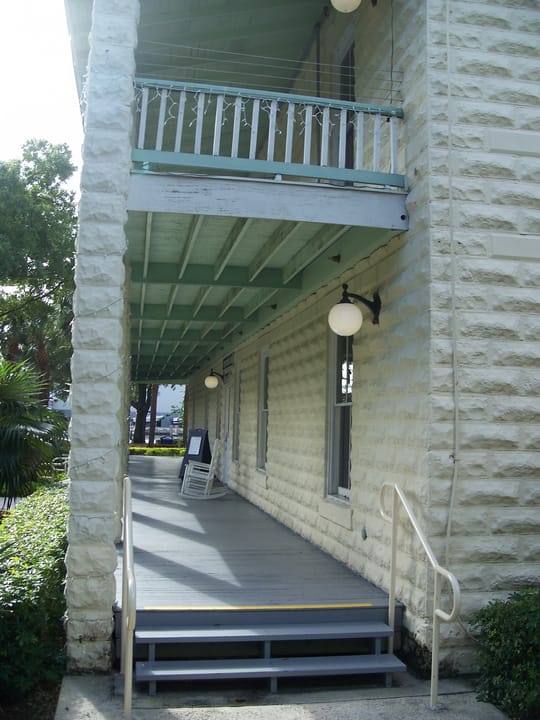 Detail of the New River Inn's covered second-floor porch, stairway and globe light fixtures along its side elevation, Fort Lauderdale, Florida, 2010.