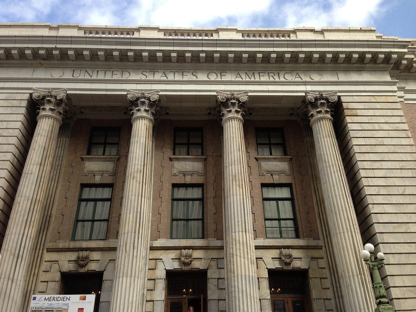 Exterior of the Old Federal Courthouse (now Le Meridien Tampa) on Florida Avenue, a 1905 Beaux Arts building with stately columns and decorative cornices.