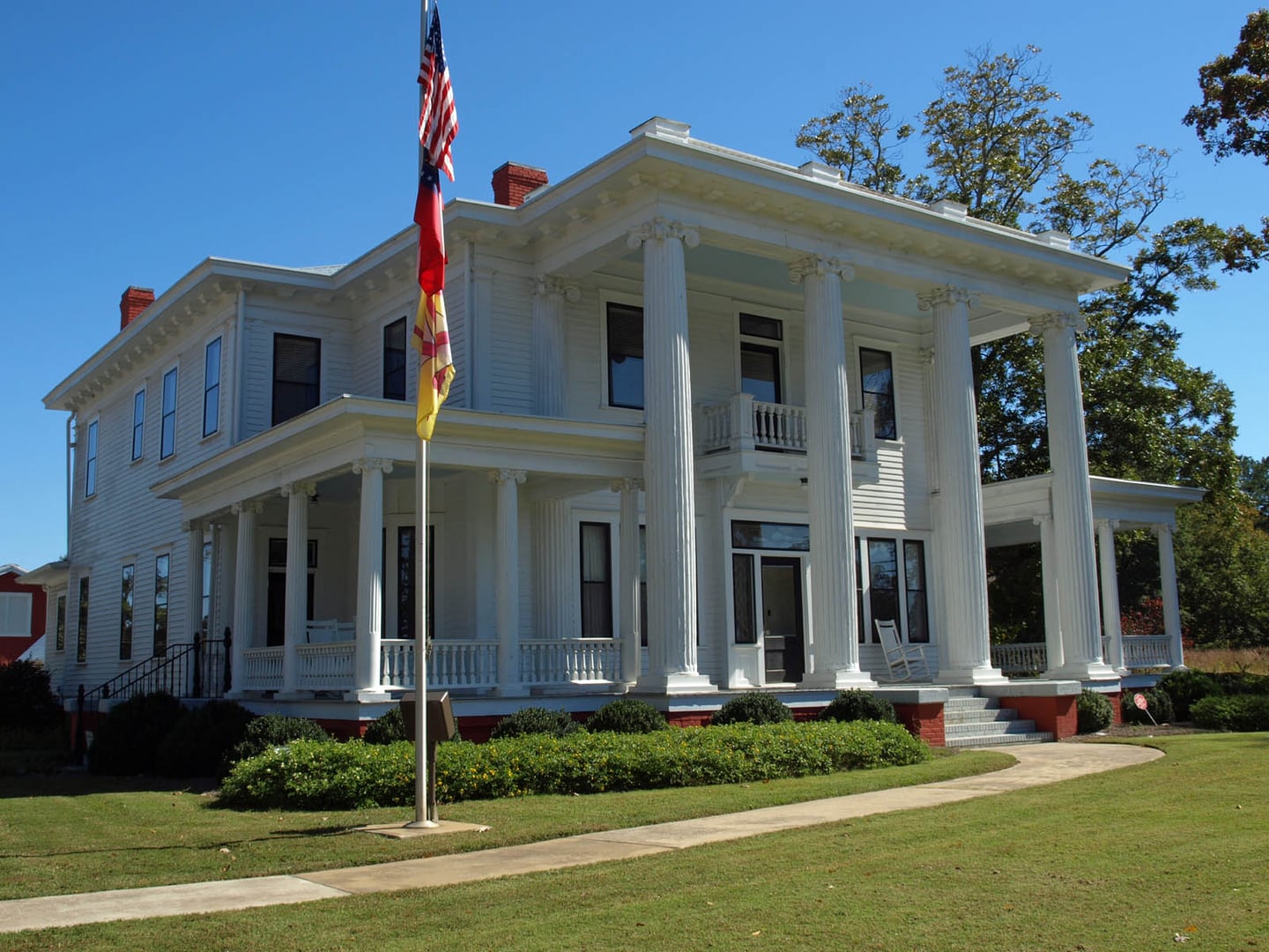 Two-story Greek Revival W.H. Braselton House with four-columned front portico and American flag, serving as Braselton Town Hall in Jackson County, Georgia