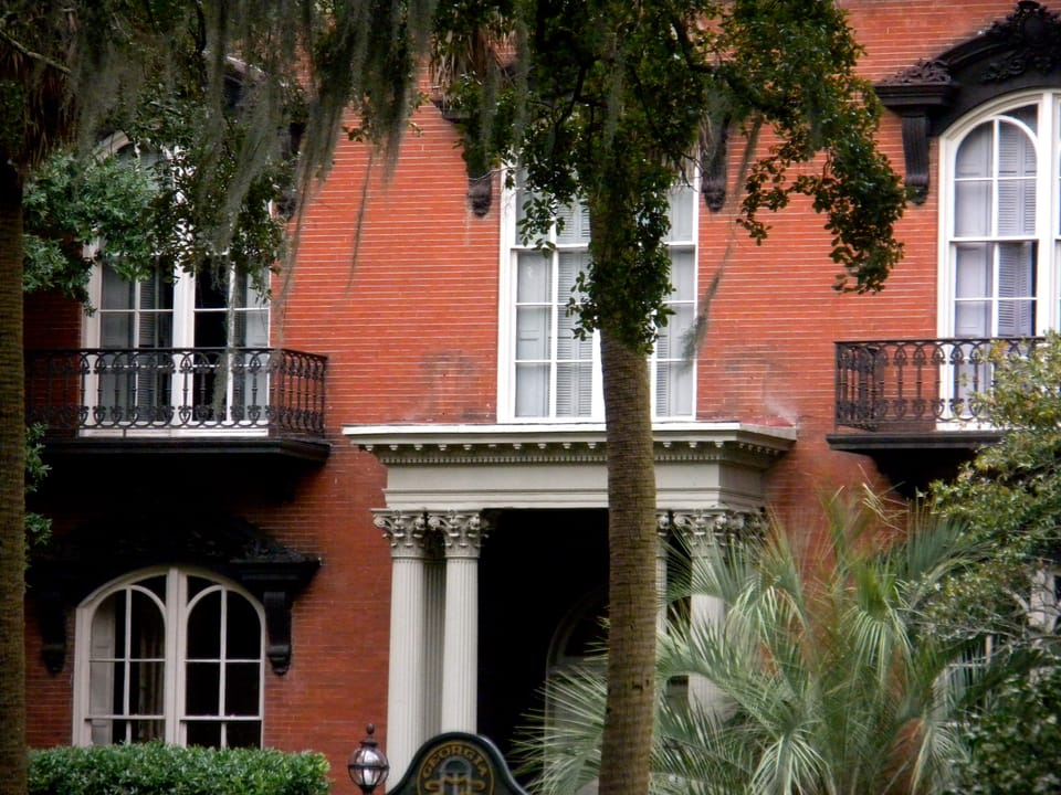A closer, angled view of the Mercer-Williams House's entrance bay and iron balconies, framed by an oak hung with Spanish moss, Savannah, Georgia, 2010.