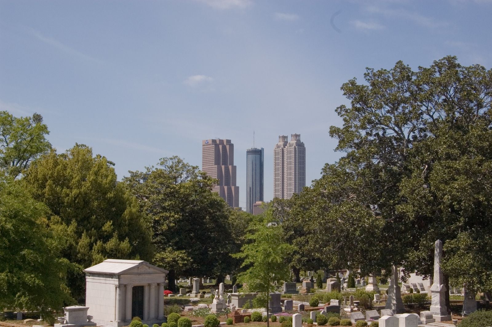 Victorian monuments and oak-lined paths of Historic Oakland Cemetery framed against the downtown Atlanta skyline.