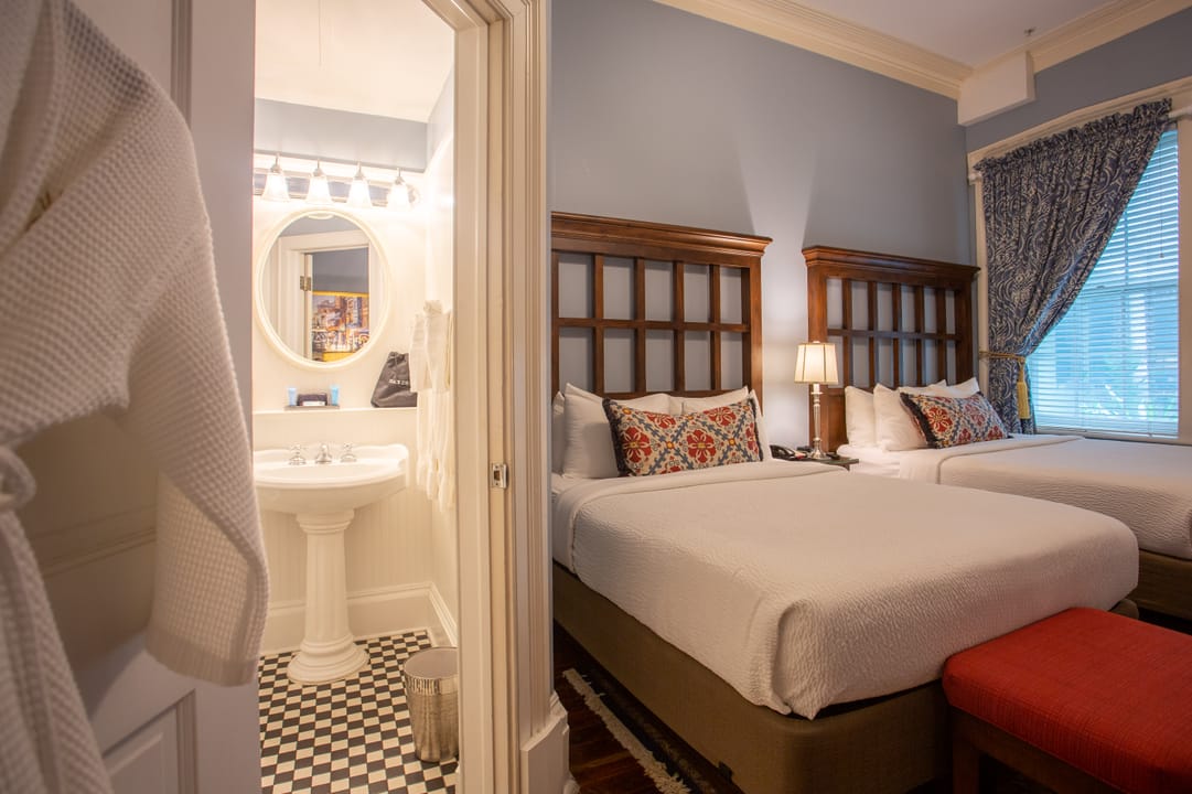 A guest room with two beds and ensuite bath at The Marshall House, Savannah.