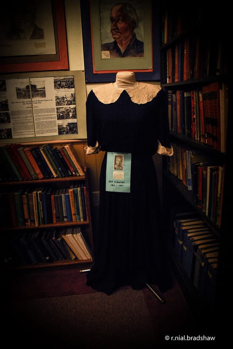Inside the Albion Normal School museum: a period dress and portrait displayed among the library's bookshelves, Albion, Idaho.