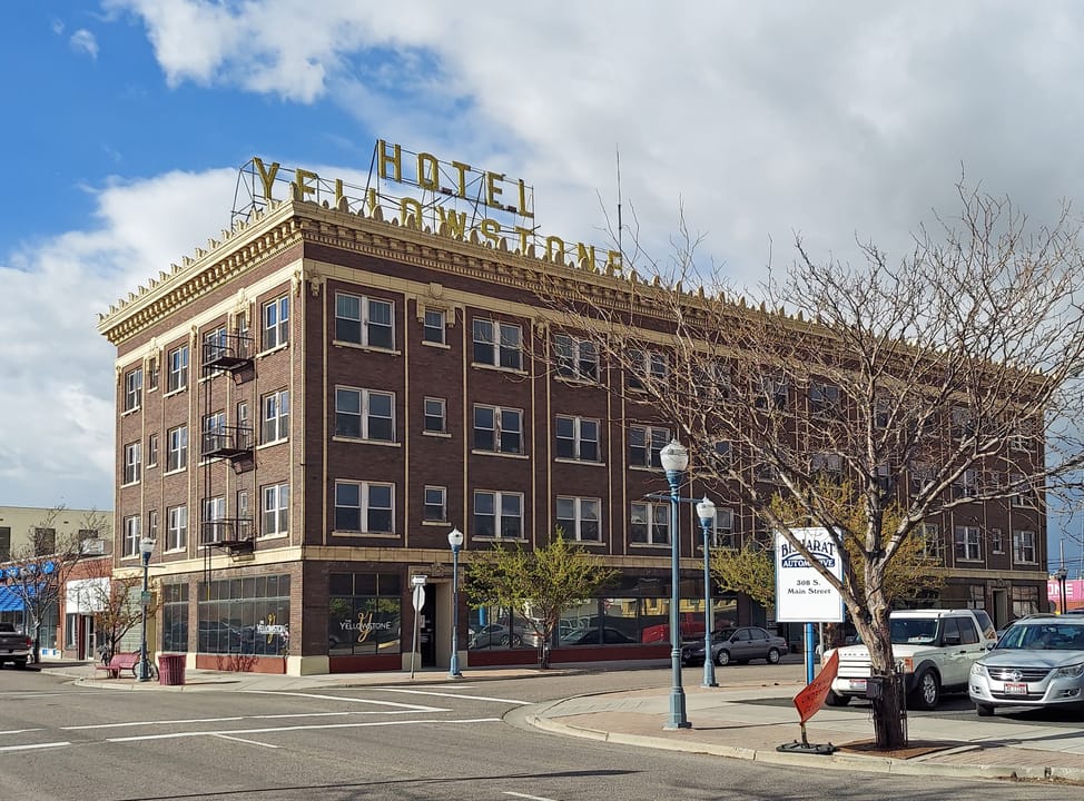 The four-story brick Hotel Yellowstone with its rooftop sign, seen across the street intersection, Pocatello, Idaho, April 2024.