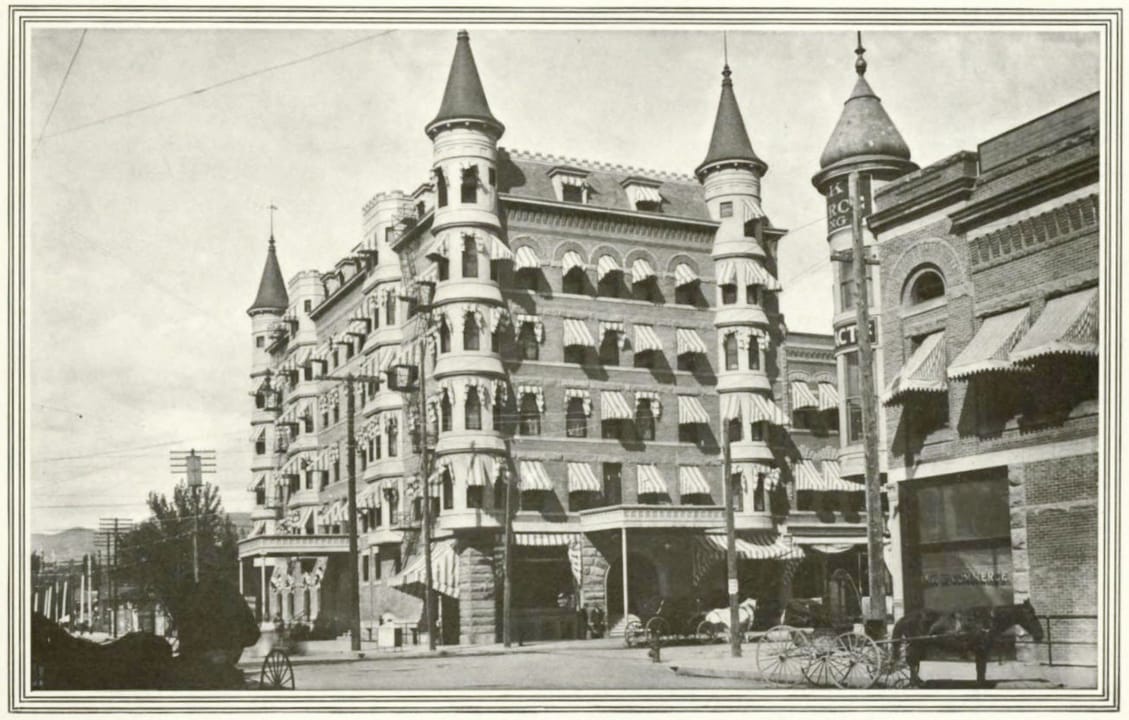 Street view of downtown Boise in 1908, showing the Idanha Hotel at left (full turreted facade and awnings) beside the since-demolished W. E. Pierce Building at right; published by the Boise Commercial Club.