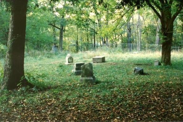Weathered headstones cluster among trees at Bachelor's Grove Cemetery in Midlothian, Illinois