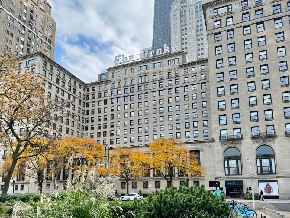 The Drake Hotel's main block and rooftop sign seen across a park on a bright autumn day, Chicago, November 2023.