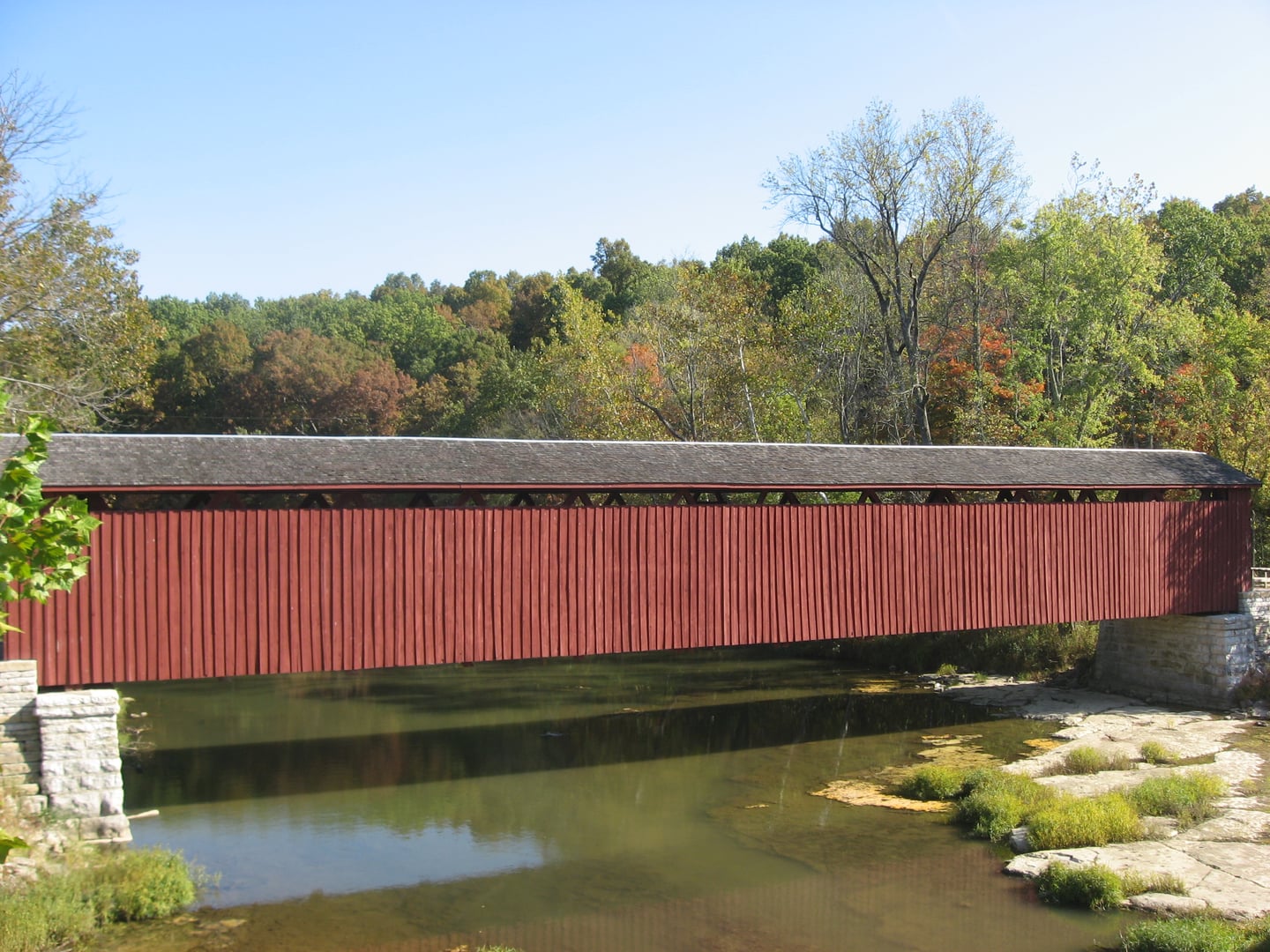 Southern (downstream) side of the Cataract Covered Bridge, which spans the White River near Cataract in Jennings Township, Owen County, Indiana, United States.  Built in 1876, it is listed on the National Register of Historic Places.