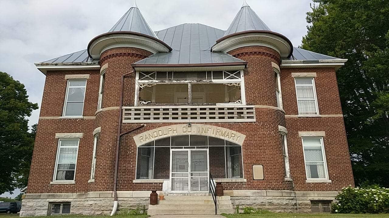 Randolph County Infirmary four-story brick building viewed from US Route 27 in Winchester, Indiana on an overcast day