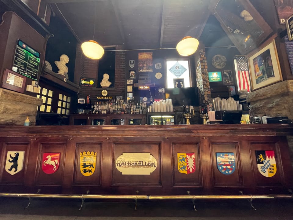 The carved wooden bar inside the Rathskeller, the Athenaeum's historic German beer hall, decorated with painted coats of arms, Indianapolis, 2022.