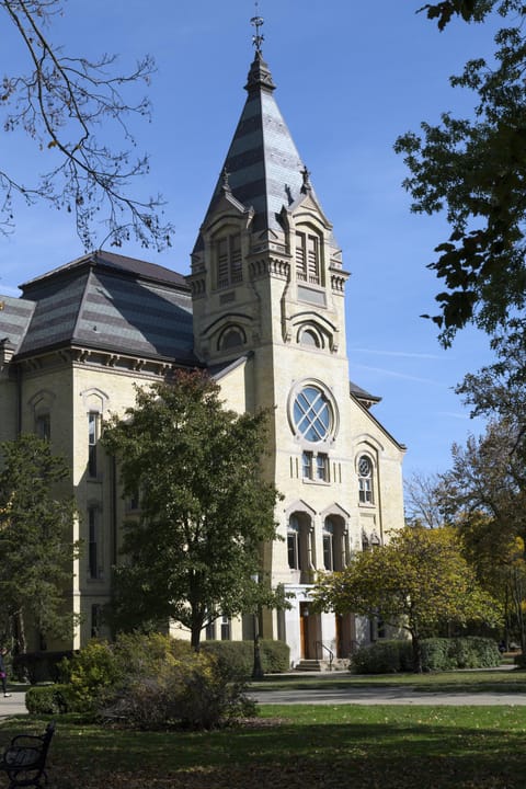 The tower and main entrance of Washington Hall (built 1881) at the University of Notre Dame, with its banded slate spire and round window, photographed in October 2012.